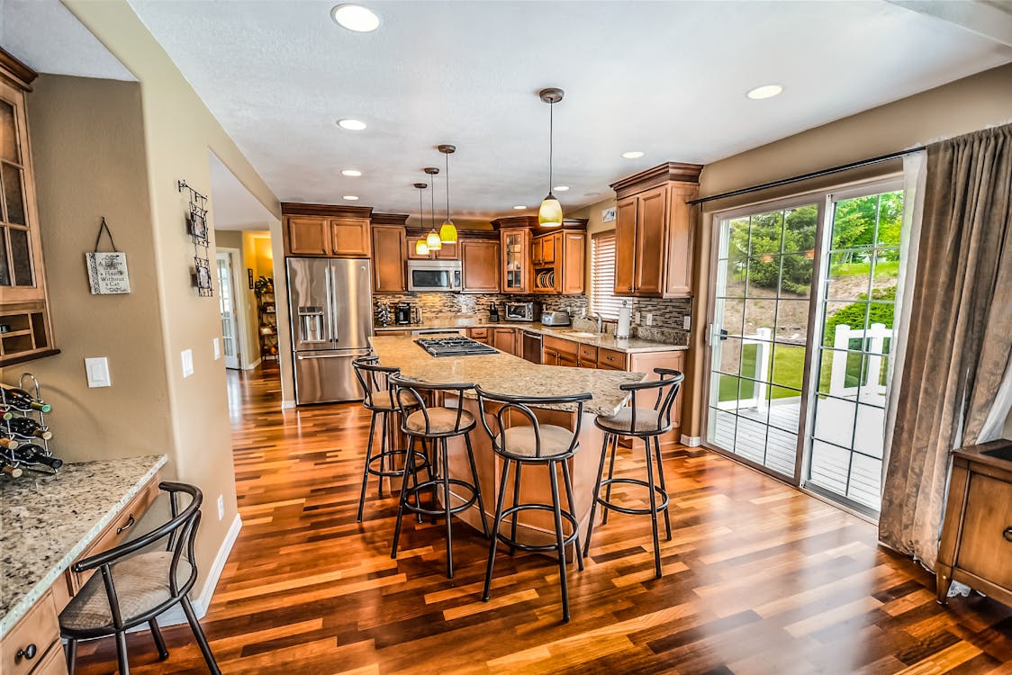 A sleek, modern kitchen provides the backdrop for a real estate agent focused on their laptop, managing client details and listings.