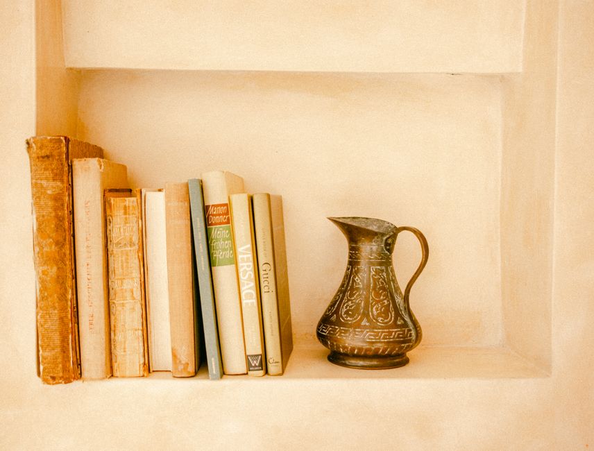 A close-up of a beautifully styled bookshelf featuring curated books and decor objects, showcasing the unique personality and thoughtful branding of a modern coastal vacation home.