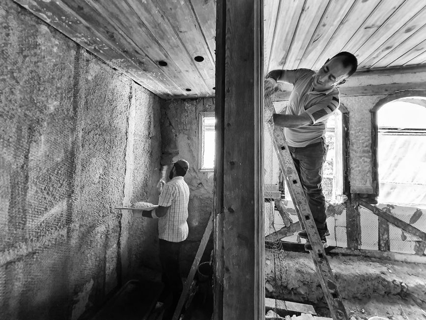 Construction worker in protective gear professionally applying expanding spray foam insulation to the rafters and ceiling ...