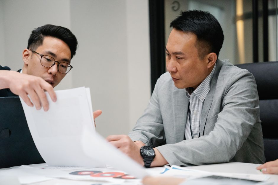 Two real estate professionals in a modern, bright office collaborating over a tablet, illustrating a strategic partnership to maximize a home sale.