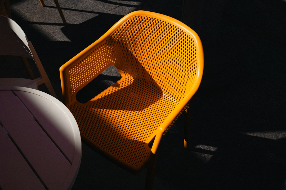 A woman peacefully enjoying a moment of relaxation in a comfortable, modern chair on a sunlit patio, conveying the premium guest experience of a branded vacation rental.