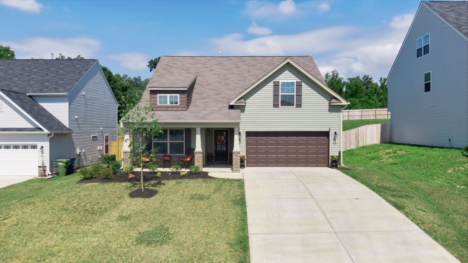 The beautiful exterior of an upscale suburban home with a welcoming front porch on a bright, sunny day, representing a successful home sale in Covington.